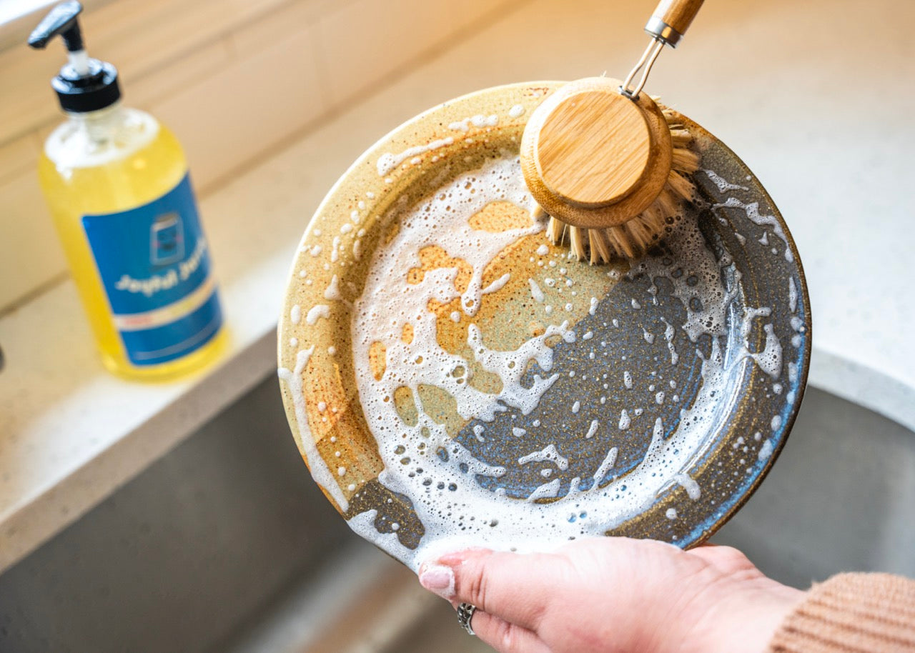 Suds from dish soap and long handled bamboo dish brush with replaceable head made with agave plant fibers