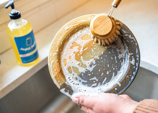 Suds from dish soap and long handled bamboo dish brush with replaceable head made with agave plant fibers