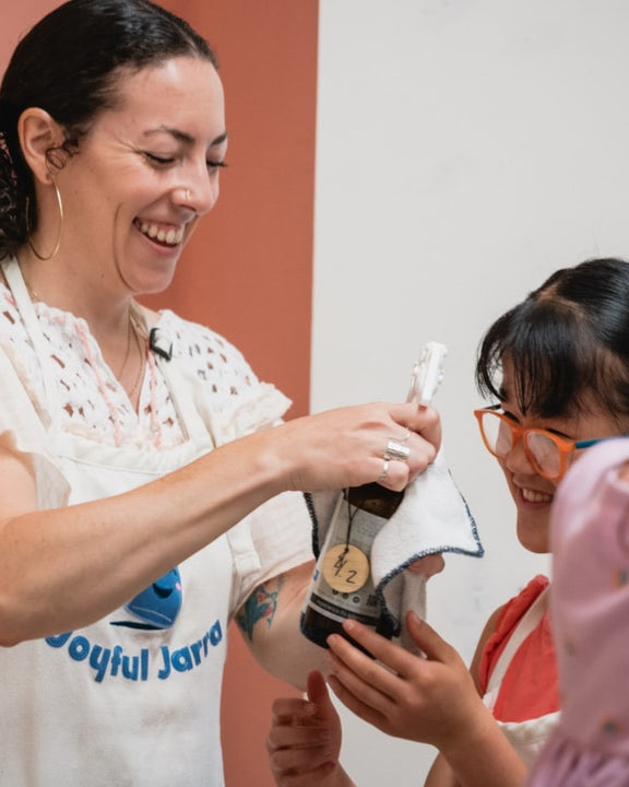 Woman holding a bottle with a child and another person in a refillery